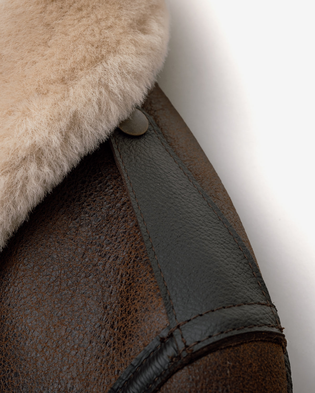 Close-up of a brown leather and fur product with a button on a white background
